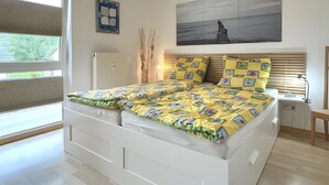 A modern bedroom with a bed, a bedside table, a lamp, a window, and a painting on the wall.