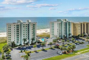 Un hotel moderno de gran altura con varios pisos, estacionamiento y vista al mar.