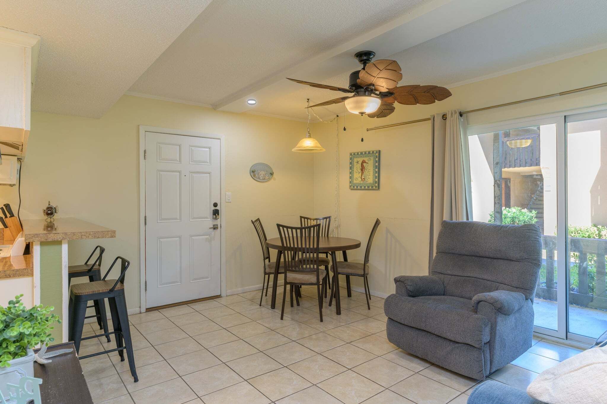 A dining area with a table and chairs, a ceiling fan, and a sliding glass door leading to an outdoor area.
