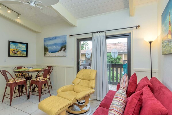 A room with a yellow chair, a red sofa, a dining table with chairs, and artwork on the walls. - 1br Resort-style Condo W/ Balcony And Pool 1 Bedroom Condo (South Padre Island)