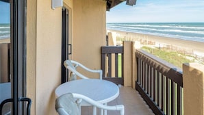 Ein Balkon mit Tisch und Stühlen mit Blick auf einen Strand.