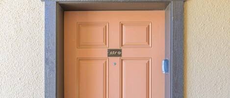 A brown door with a number plate, a doorbell, and a mail slot.