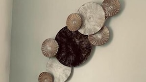 Pieza decorativa montada en la pared con elementos circulares en varios tonos.