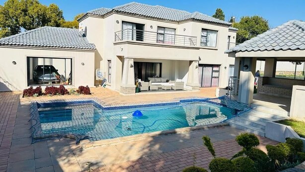 Una casa de dos pisos con piscina, garaje y un espacio cubierto para sentarse al aire libre.