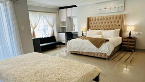 Un dormitorio moderno con una cama grande, una mesita de noche, una silla y un sofá.