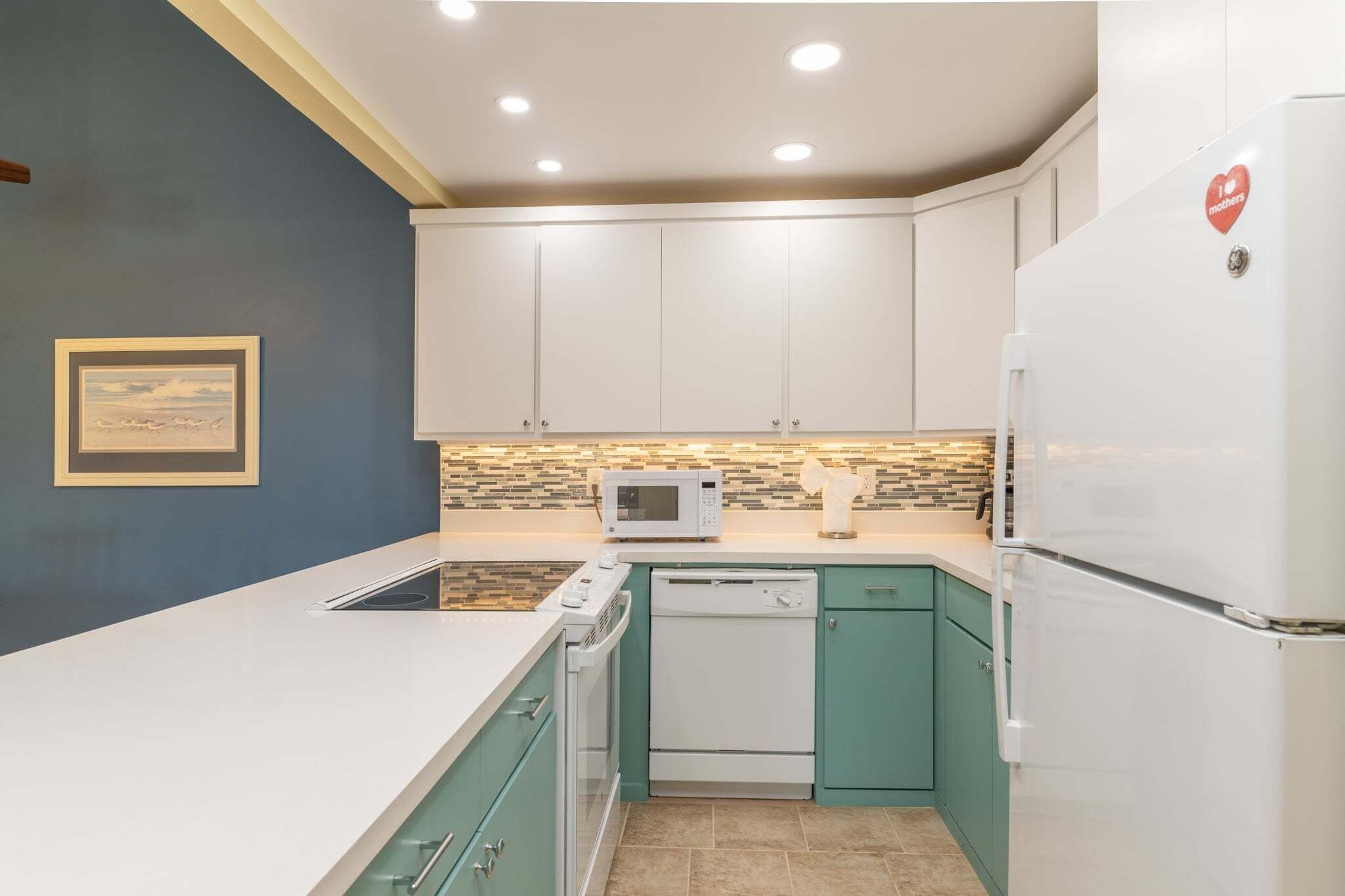 A modern kitchen with white cabinets, a microwave, a dishwasher, and a refrigerator.