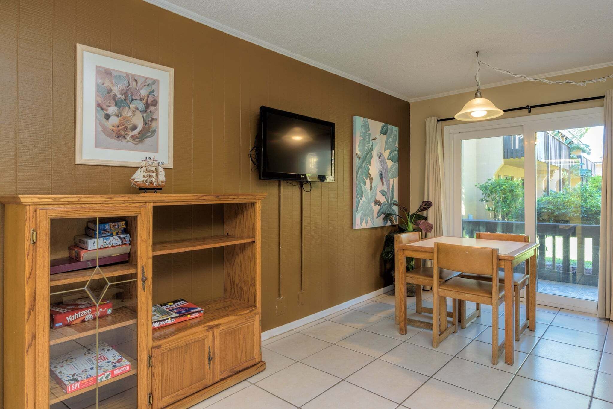 A living room with a wooden cabinet, a television, and a dining table with chairs.