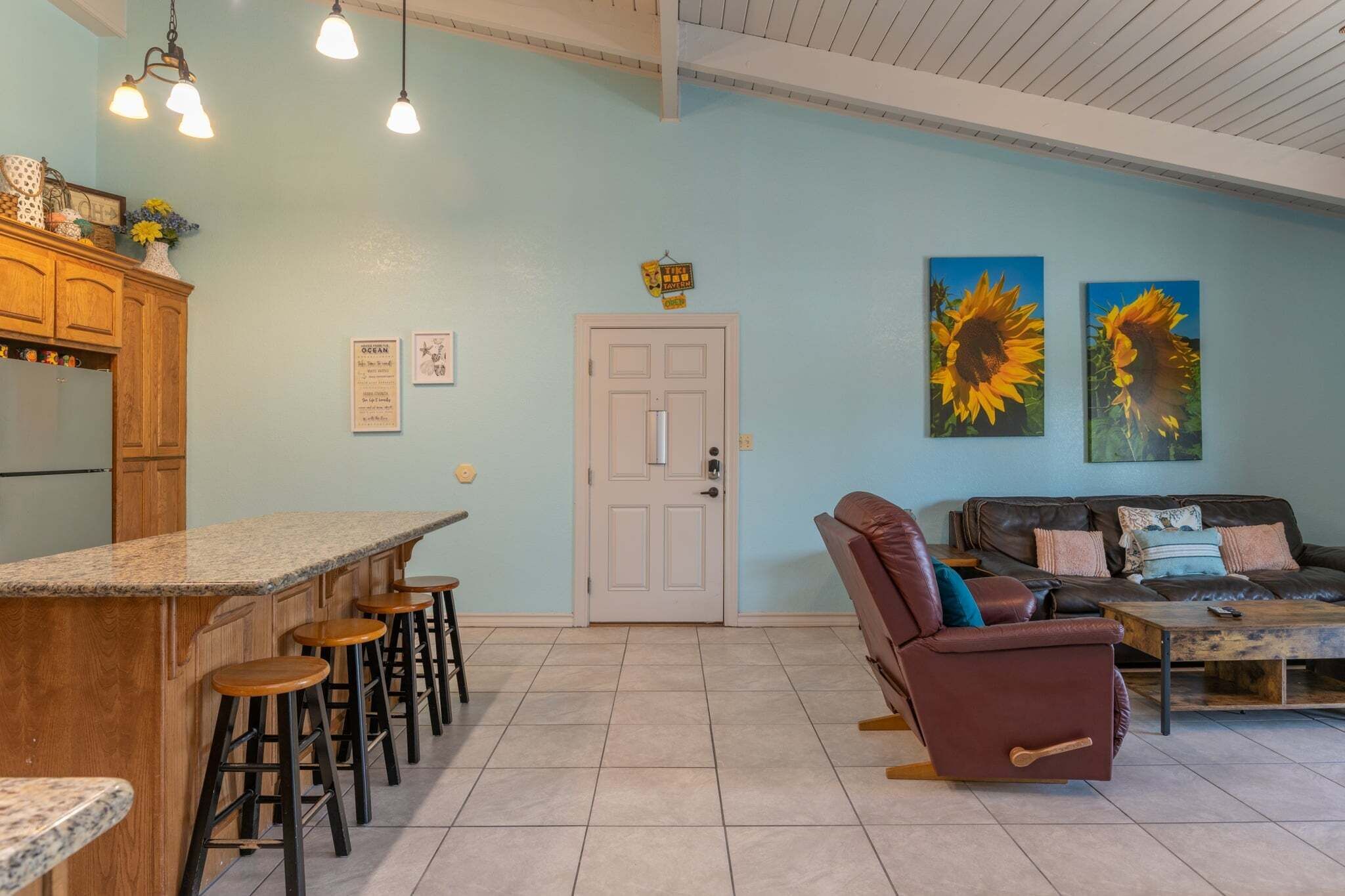Una cocina con barra, una puerta y una sala de estar con sofá y sillón reclinable.