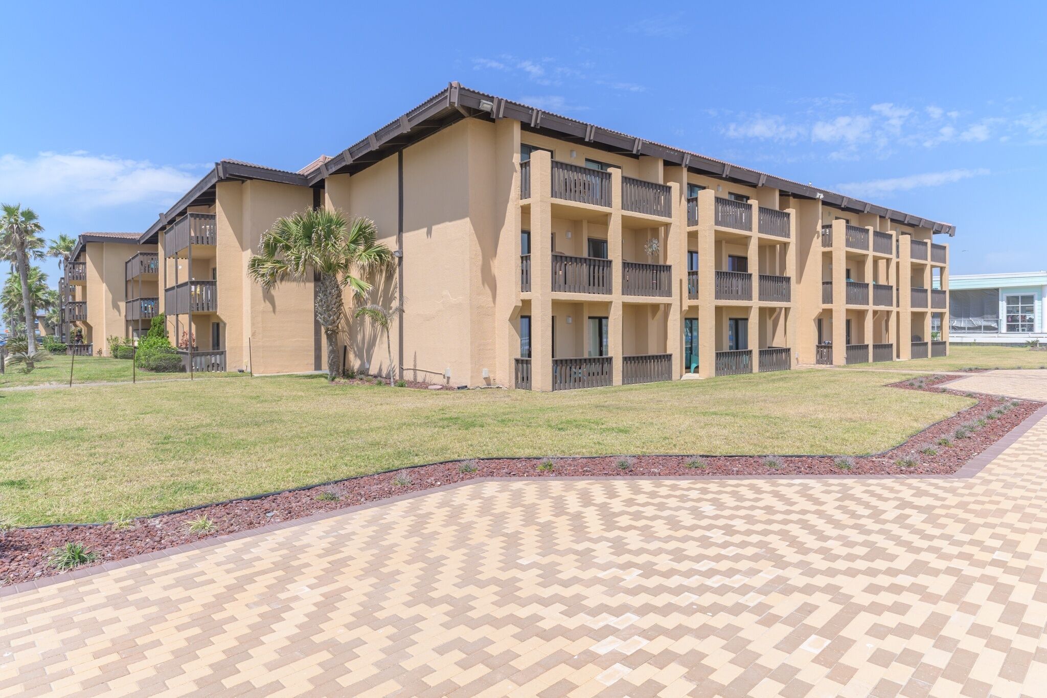 A multi-story hotel with a beige facade, balconies, and a paved courtyard.