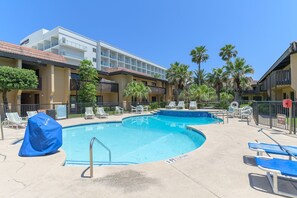 Ein Hotel mit Swimmingpool, Liegestühlen und Palmen.