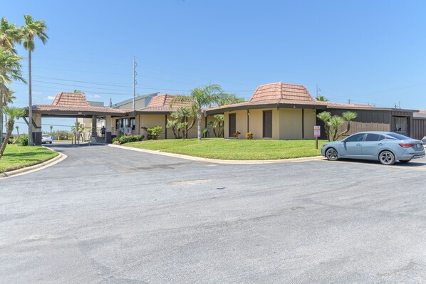 A hotel with a covered entrance, palm trees, and a parked car. - Tiki 337 - Oceanview Condo W/ Pools & Beach Access 1 Bedroom Condo (South Padre Island)