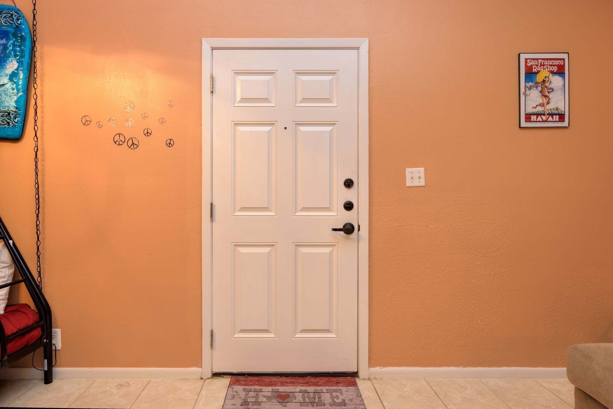 A white door with a keyhole and a doorknob, a wall with a poster, and a bunk bed with a chain.