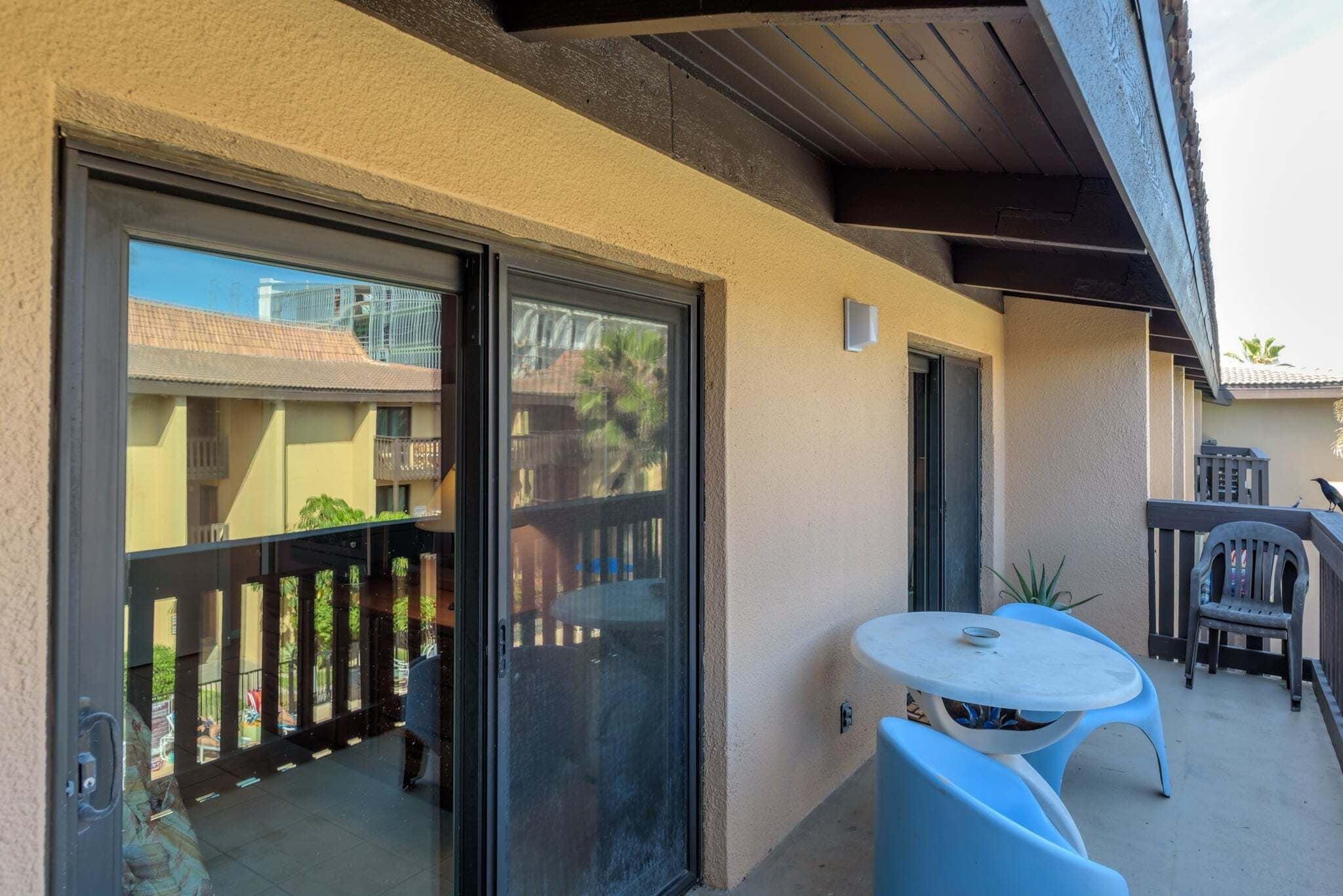 Ein Balkon mit Schiebeglastür, einem kleinen Tisch und zwei Stühlen.