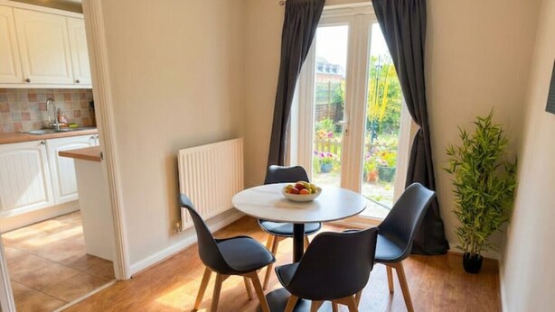 Un coin repas avec une table ronde, quatre chaises et un saladier rempli de fruits.
