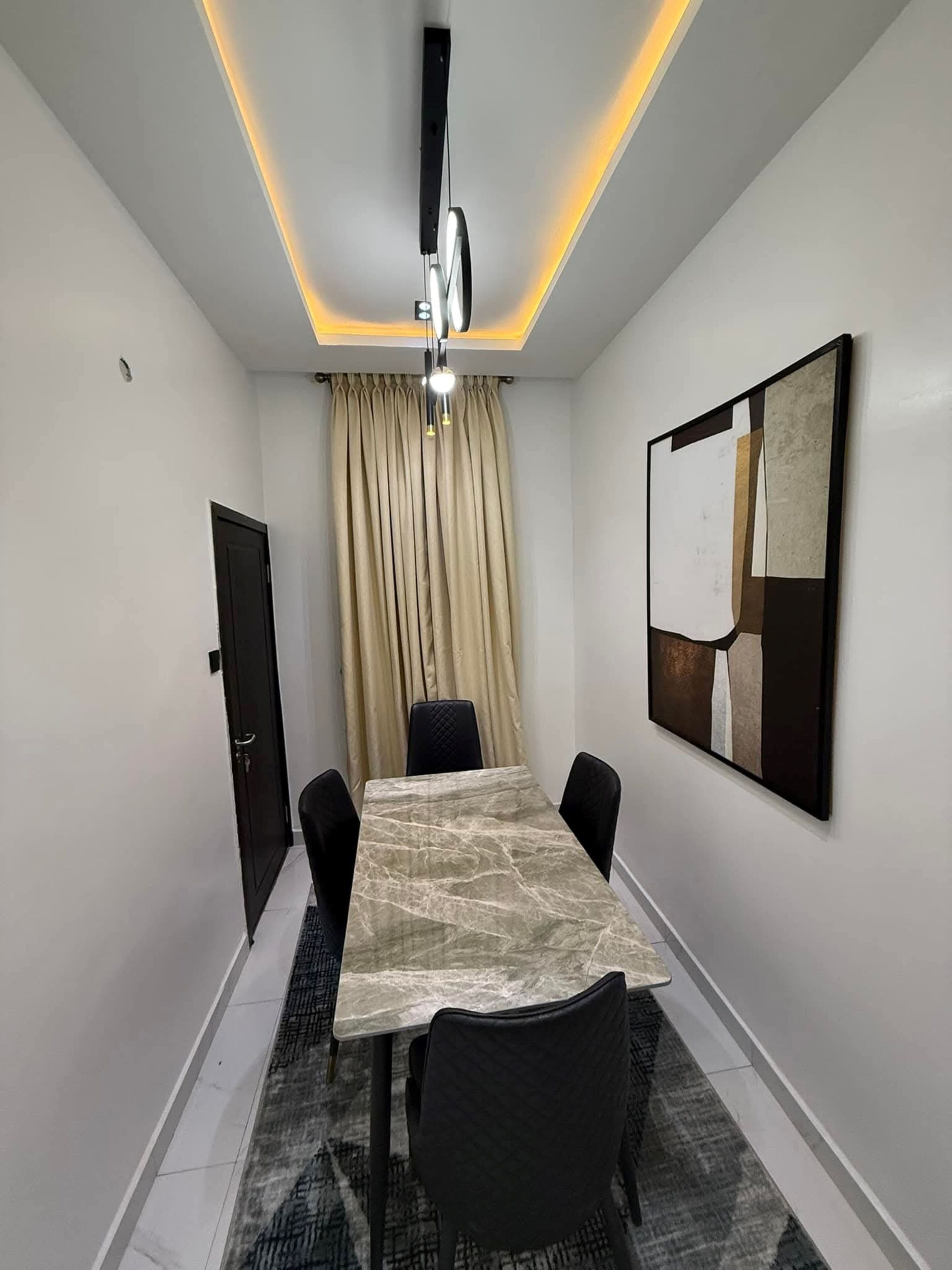 A conference room with a marble table, black chairs, a ceiling light, a door, and a large abstract painting on the wall.