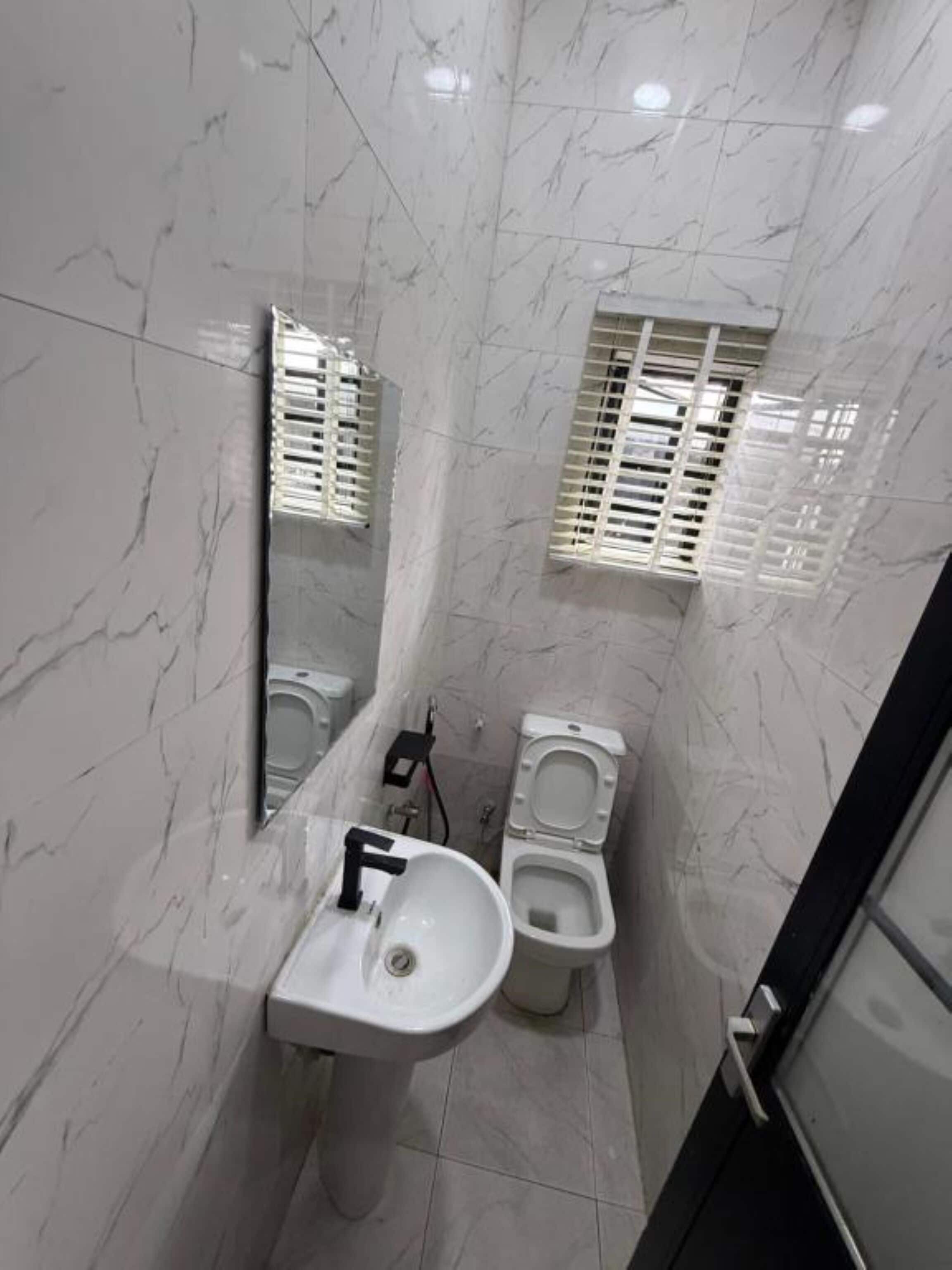 A bathroom with a white sink, a mirror, and a toilet.