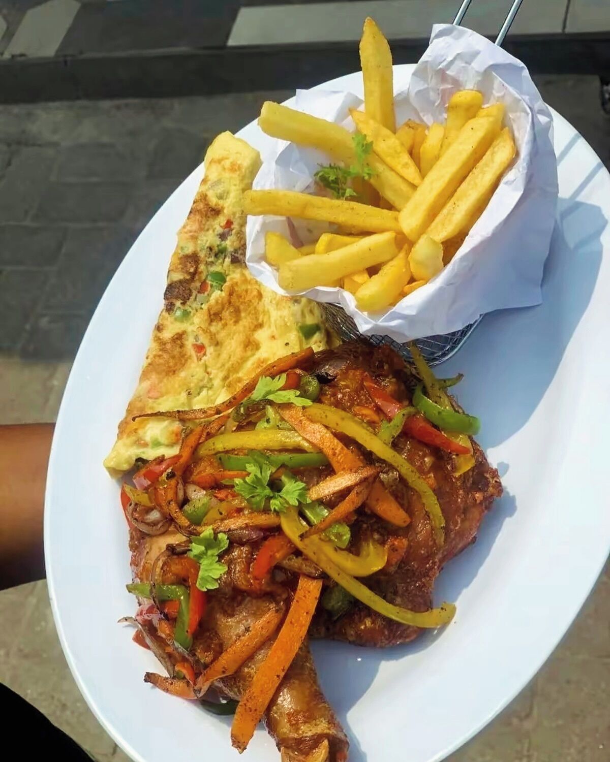 Une assiette comprenant un plat de viande grillée, des frites et une tranche de pain grillé.