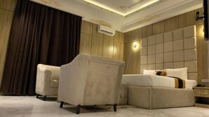 A hotel room with a large bed, a sofa, a chair, and a nightstand. - Remalex Hotel and Suites (Uyo)
