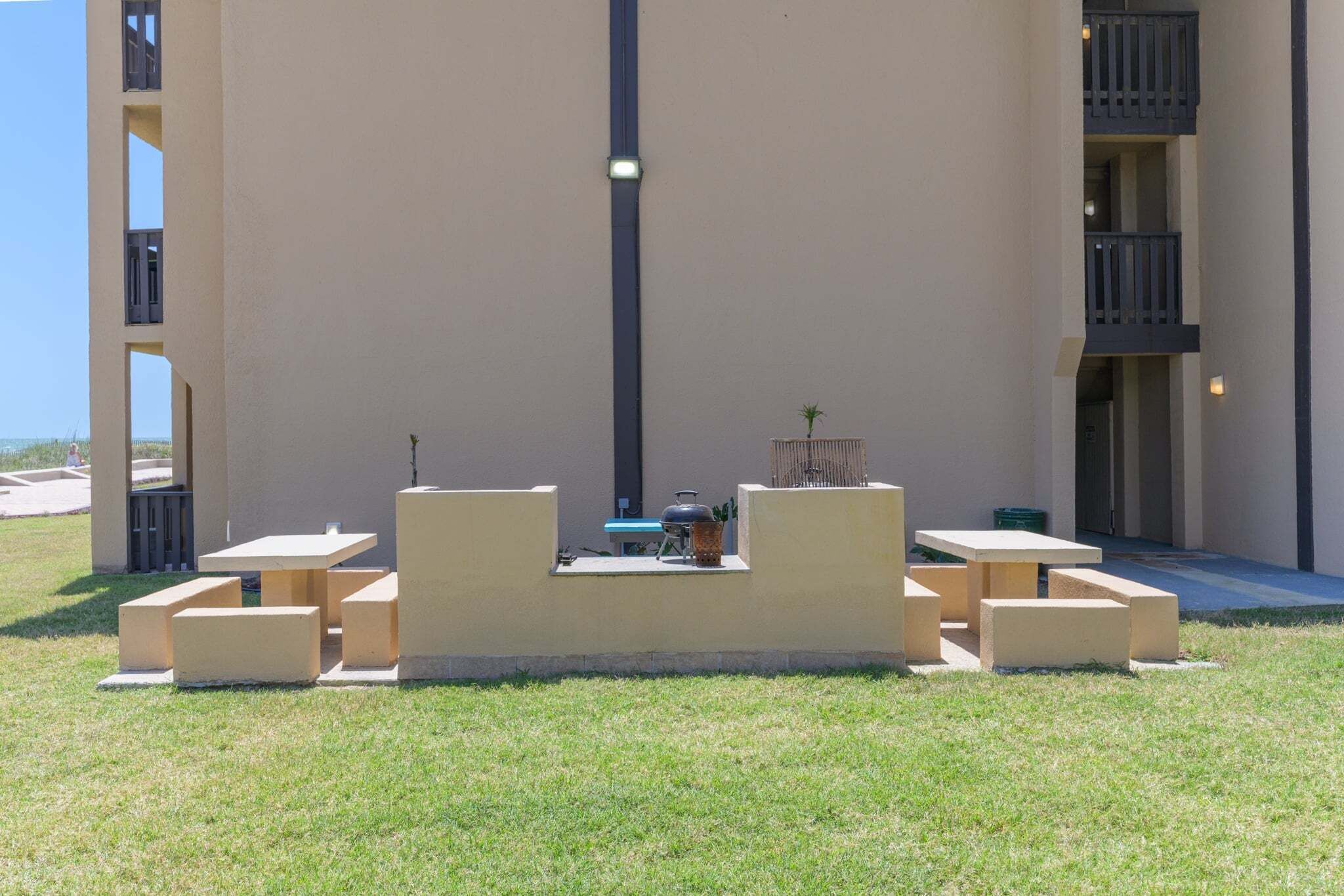 A courtyard with outdoor seating, a barbecue grill, and a small table with a plant.