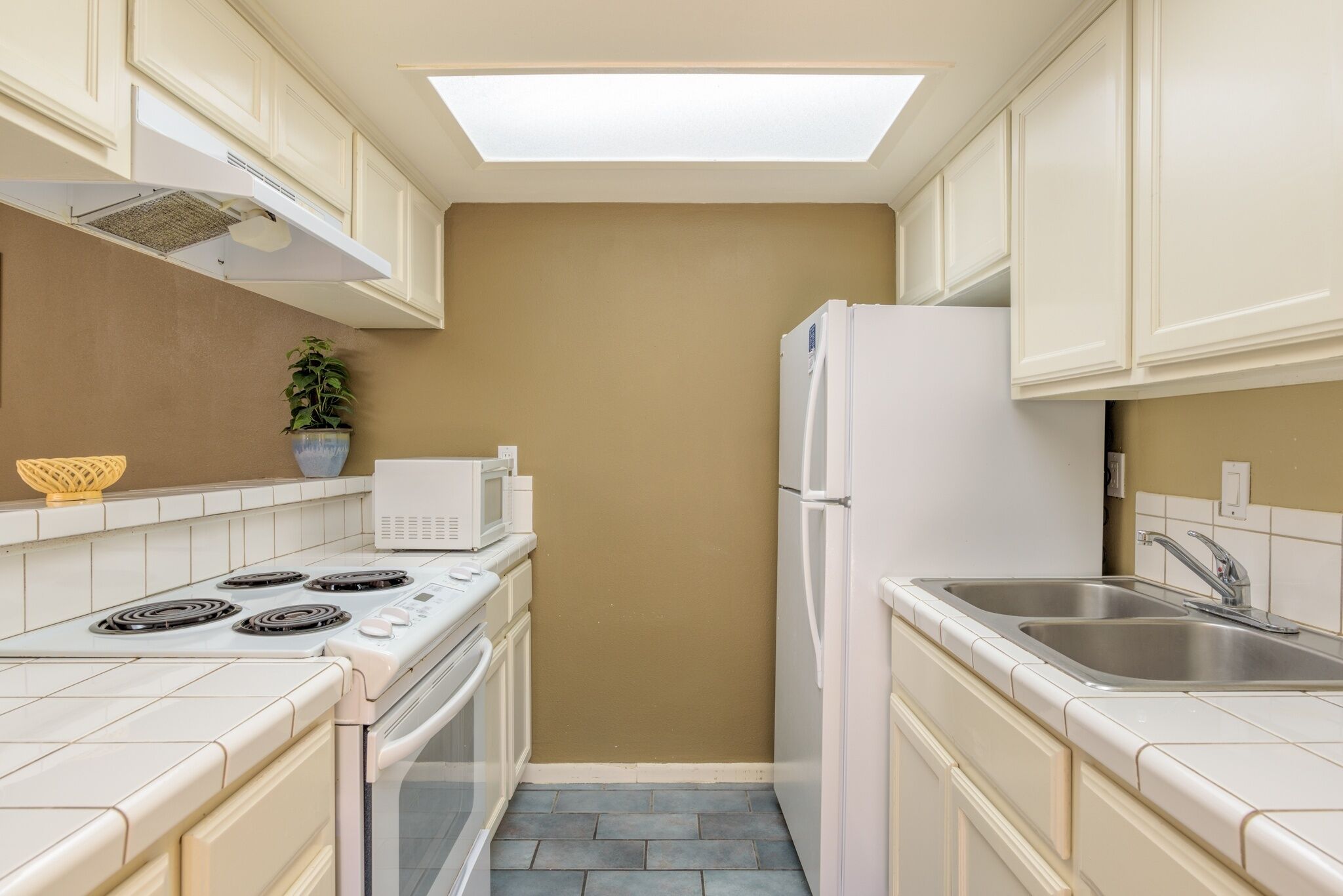 A compact kitchen with a microwave, stove, oven, and refrigerator.