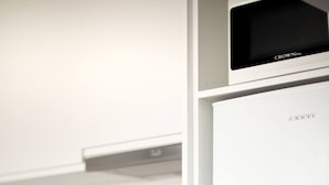 Een moderne keuken met een witte koelkast, een magnetron en een fornuis.