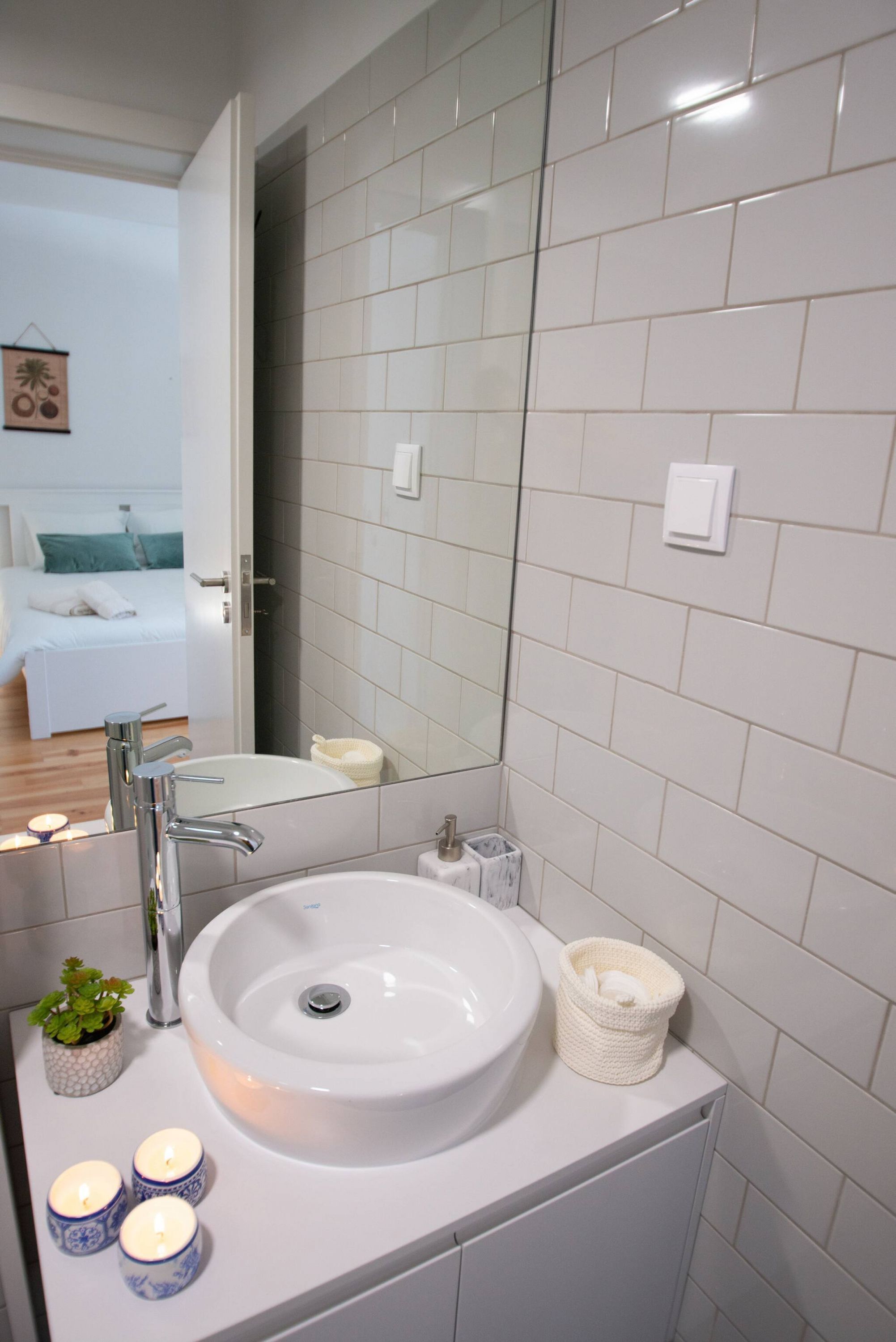 A modern bathroom with a white sink, mirror, and tiled walls.