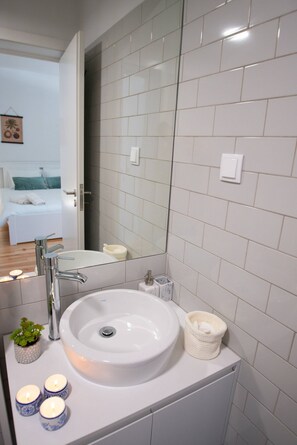 A modern bathroom with a white sink, mirror, and tiled walls. - Guest H4U - Porto City Center (Porto)
