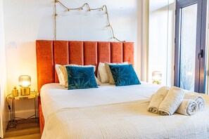 Une chambre d’hôtel avec un grand lit, une tête de lit rouge en tissu et deux lampes de chevet.