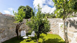 A stone wall, a small tree, and two white chairs in a garden area. - Guesth4u Heroismo Garden Delight (Porto)