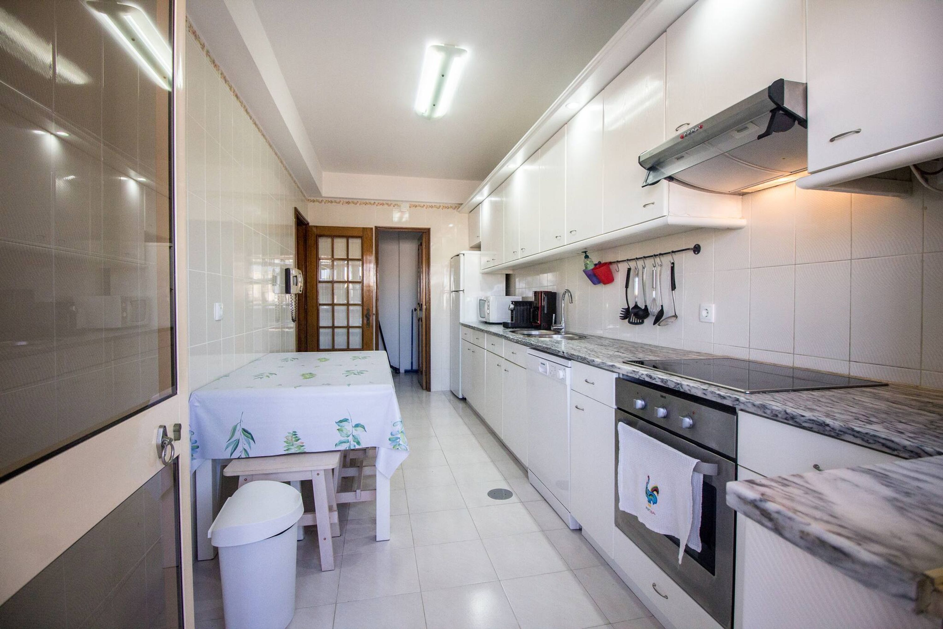 Une cuisine de taille réduite avec des meubles blancs, une cuisinière et un four à micro-ondes.