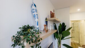 A modern bathroom with a wooden shelf holding a blue and white patterned towel, a small framed picture, and a potted plant. - Guest H4U - Heroismo 2F (Porto)