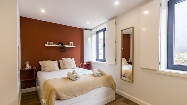 A bedroom with a bed, a bedside table, a nightstand, a window, and a mirror. - Guest H4U - Heroismo 2F (Porto)
