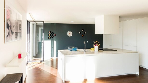 A modern kitchen with a central island, white cabinetry, and a dark accent wall. - Guest H4U - Bonjardim Pop Art (Porto)