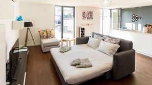 A modern bedroom with a bed, bedside table, lamp, and a view of the outside. - Guest H4U - Bonjardim Pop Art (Porto)
