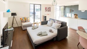 A modern bedroom with a bed, bedside table, lamp, and a view of the city through the window. - Guest H4U - Bonjardim Pop Art (Porto)