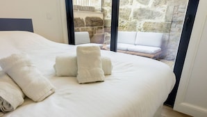 A bedroom with a large bed, white linens, and several rolled towels. - Guest H4U - Hero smo Terrace Ground Floor (Porto)