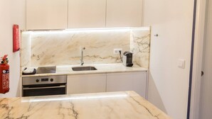A modern kitchen with a marble countertop, stainless steel appliances, and pendant lighting. - Guest H4U - Hero smo Terrace Ground Floor (Porto)