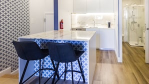 A modern kitchen with a marble countertop, two bar stools, and a built-in island. - Guest H4U - Hero smo Terrace Ground Floor (Porto)