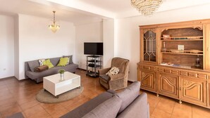 A modern living room with a grey sofa, a white coffee table, a wicker armchair, and a wooden cabinet. - Guest House 4U - Povoa Seaside (Povoa De Varzim)