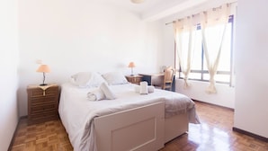A neatly arranged bedroom with a bed, two bedside tables, a desk, and a chair. - Guest House 4U - Povoa Seaside (Povoa De Varzim)