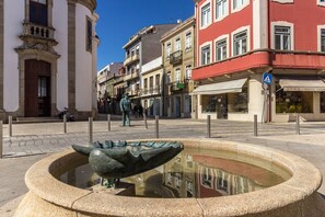 A public square with a central fountain, surrounded by historic buildings with balconies and storefronts. - Guest H4U - P voa Summer (Povoa De Varzim)