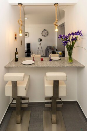 A modern kitchen with a central island, two bar stools, a wine bottle, and a vase of flowers. - Guest H4U - Povoa Design (Povoa De Varzim)