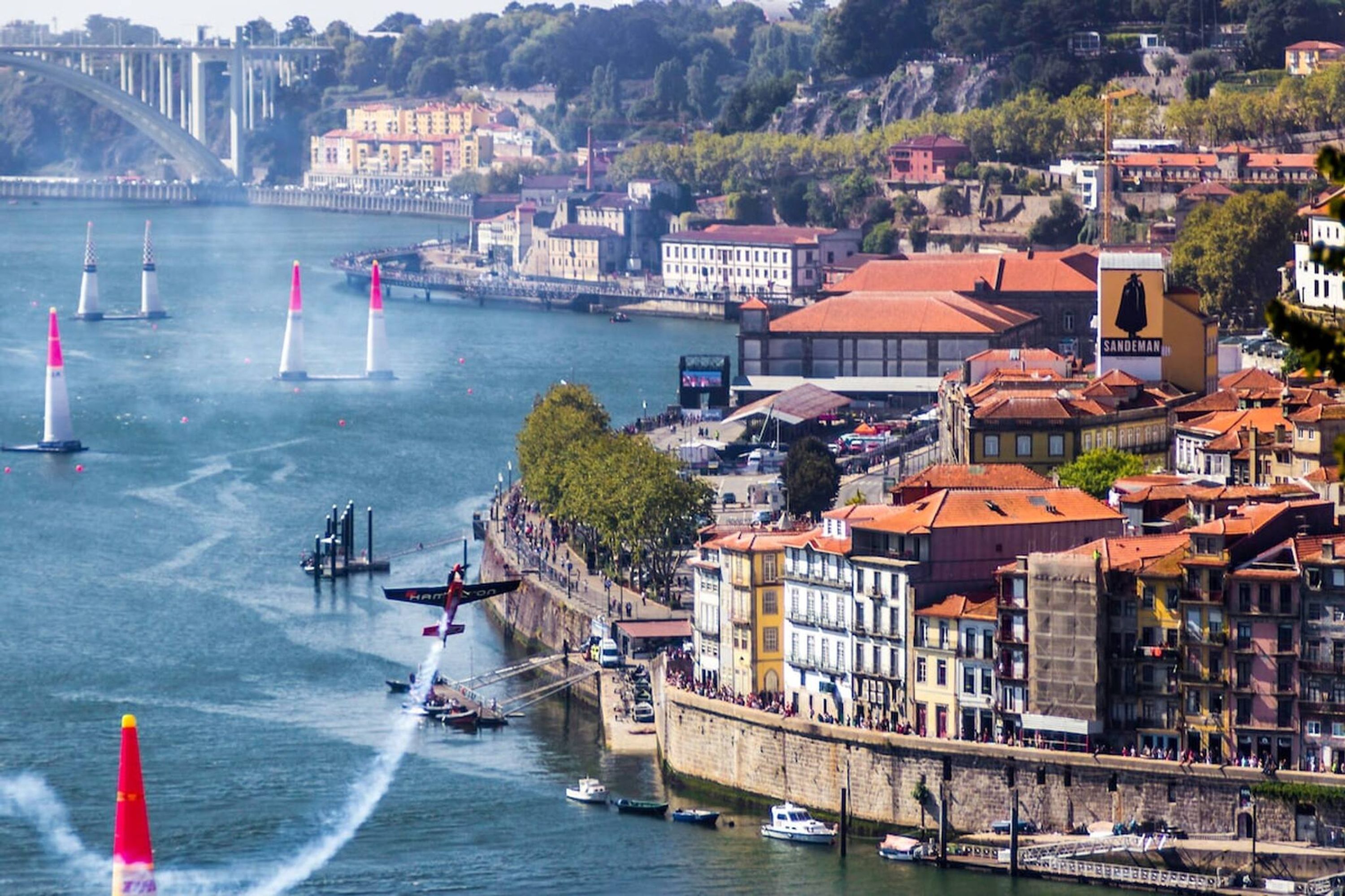 Ein Fluss mit Booten und einem Jetski, umgeben von historischen Gebäuden mit roten Dächern.