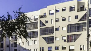 Um edifício residencial moderno de vários andares, com varandas, janelas amplas e telhado plano.