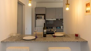 Uma cozinha com ilha central, dois bancos altos e um lustre.