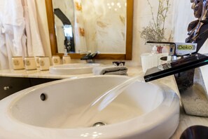 Ein Badezimmer mit einem großen weißen Waschbecken, einem Spiegel und einer Zierstatue.
