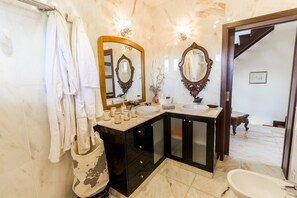 Ein Badezimmer mit Marmorboden, Waschbecken mit Spiegel und einer Badewanne.