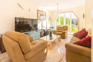 A living room with a large flat-screen TV, two sofas, a coffee table, and a glass-top coffee table. - Guest H4U Villa Garden Pool (Povoa De Varzim)