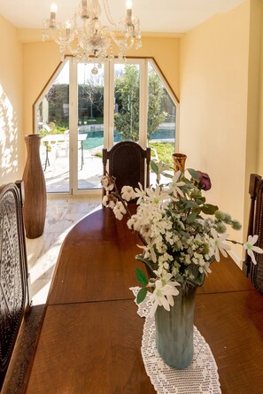 A dining table with a vase of flowers, a chandelier, and a view of the outdoors. - Guest H4U Villa Garden Pool (Povoa De Varzim)