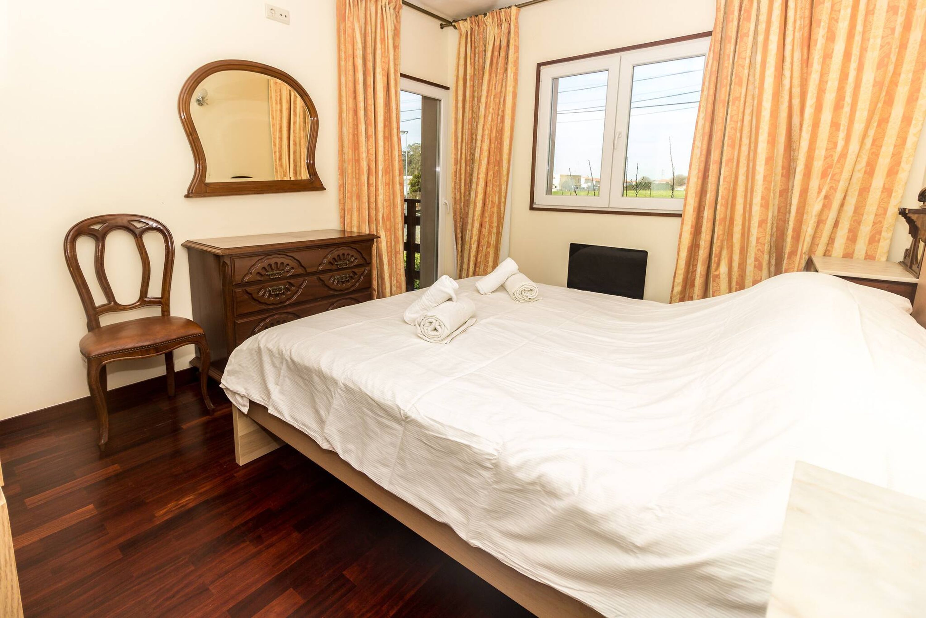 Ein Hotelzimmer mit einem großen Bett, einer Holzkommode und einem Spiegel an der Wand.